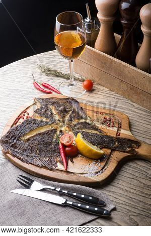 Fried Fish Served On Wooden Board With Glass Of White Wine