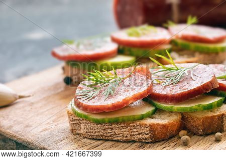Sandwich With Smoked Sausage And Vegetables On Rye Piece Of Bread On Cutting Board,  Harmful Fast Fo