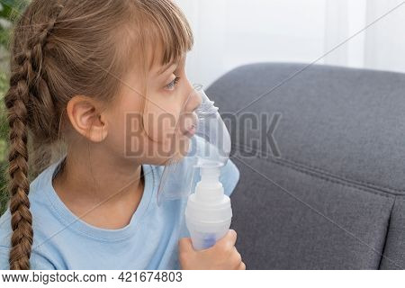 Little Girl Making Inhalation With Nebulizer At Home. Child Asthma Inhaler Inhalation Nebulizer Stea