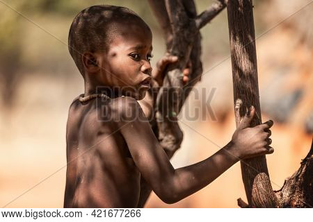 OPUWO, OTJIWARONGO REGION NAMIBIA - MAY 4, 2021: Young unidentified Himba boy with the typical necklace in Himba living museum during a appearance in front of tourists