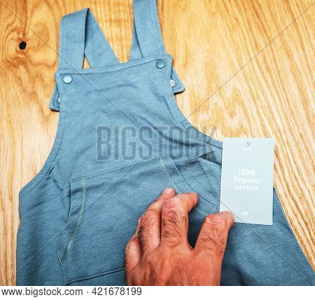Lyon, France - May 2, 2021: Pov Male Hand Father Holding Infant Baby Clothes Manufactured By The Swe