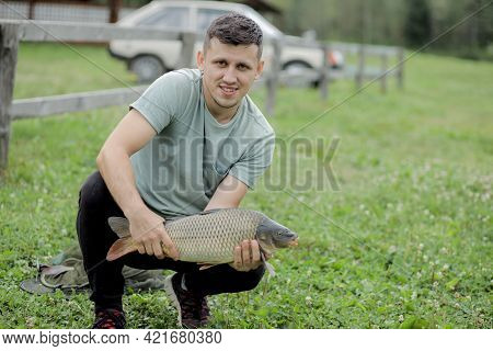 Happy Angler Holds Trophy Carp. Man With Carp Fish. Outdoors Activities, Fishing, Catching Fish Conc