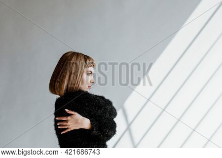 Short hair woman in a black fluffy sweater hugging herself