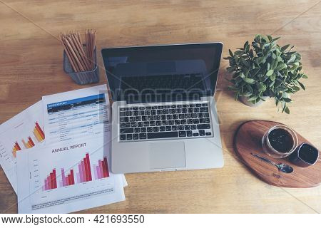 Office Laptop Business Financial Document Chart And Graph On Wooden Table With Coffee Cup. Flat Lay 