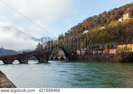  Ponte della Maddalena Bridge. Bridge built a thousand years ago. Cold green waters of the Sercchio River. The vicinity of the city of Lucca. Cold windy winter day. Italy