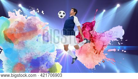 Composition of football player with ball over colourful splodges and sports stadium background. sports event and competition concept digitally generated image.