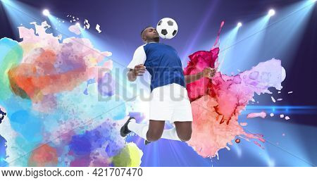 Composition of football player with ball over colourful splodges and sports stadium. sports event and competition concept digitally generated image.