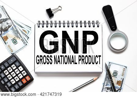 Gnp .gross National Product. Notebook On White Workspace. Near The Notepad Dollar Bills And A Calcul