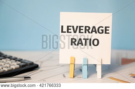 Concept Leverage Ratio On Cubes Against Blue Background Near Calculator And Financial Reports.