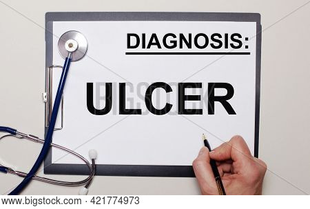 On A Light Background, A Stethoscope And A Sheet Of Paper, On Which A Man Writes Ulcer. Medical Conc