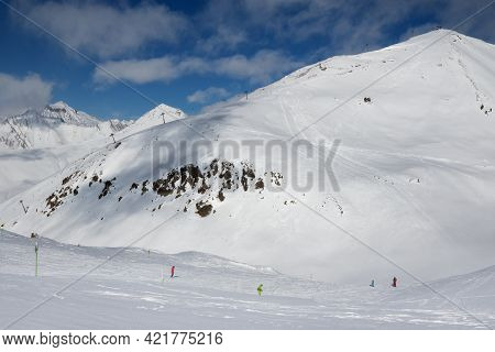 Skiers And Snowboarders Downhill On Freeride Trace And Mountains With Clouds At Sun Cold Day. Caucas