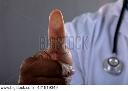 Mid section of african american male doctor scanning thumb against invisible screen. medical research and technology concept