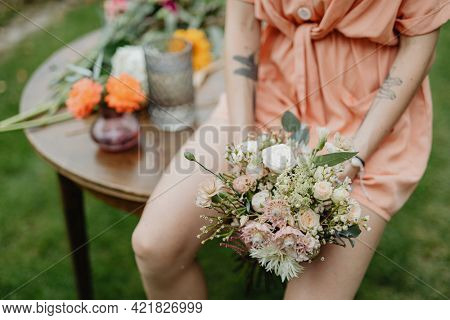 Woman in an orange jumpsuit with a bouquet of flowers