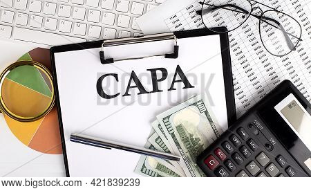 Text Capa On Office Desk Table With Keyboard,dollars,calculator ,supplies,analysis Chart On The Whit