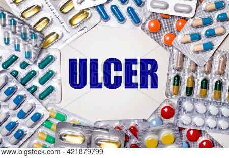 The Word Ulcer Is Written On A Light Background Surrounded By Multi-colored Packages With Pills. Med