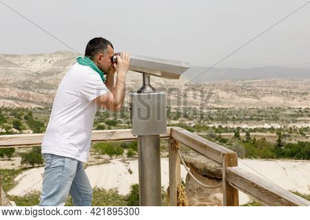 A Man Looks Through Binoculars, Enjoying A Beautiful View From A High Mountain - A Telescope At The 