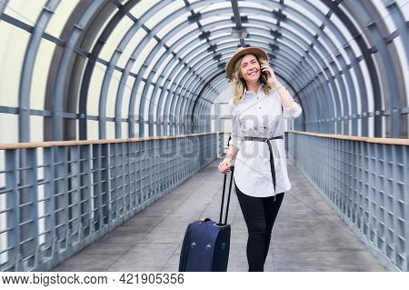 Woman Tourist With A Suitcase Smiling Walks Along The Covered Walkway Gallery, Speaks By Phone