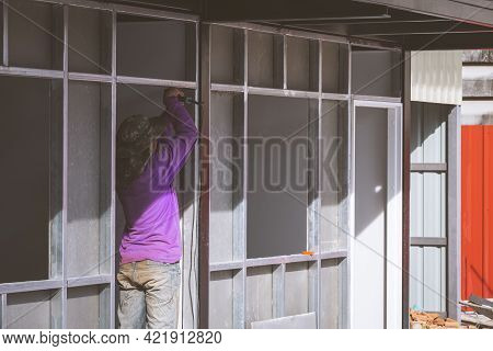 Perspective Side View Of Asian Construction Worker Installing Precast Concrete Wall In House Constru