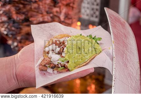 Delicious Adobada Taco With Cilantro, Onion, Guacamole And A Piece Of Mexican Style Pineapple Held B