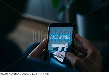 a young caucasian man, at home, uses a password manager in his smartphone, with a simulated password manager app in its screen