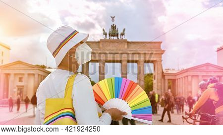 Mature Caucasian Lgbt Woman In Berlin With Rainbow Fan And Ribbon On White Summer Hat. Rainbow, Symb