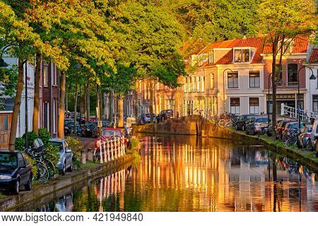 Delt canal with old houses and cars parked along on sunset. Delft, Netherlands