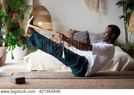 African Man Practicing Yoga Indoors Doing Boat Pose Or Paripurna Navasana