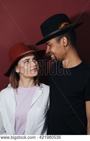 Portrait Of Happy Multiracial Couple Hugging And Posing Together Over Burgundy Wall In Studio, Roman
