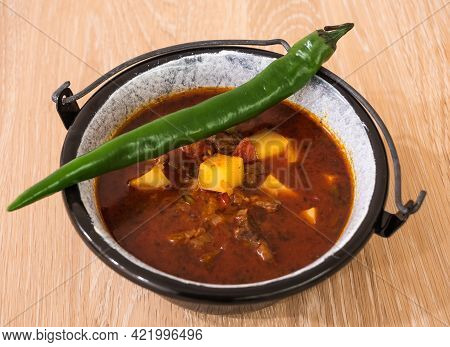 Hungarian Beef Goulash Or Gulyas Soup Or Stew Served In A Small Cauldron With Potatoes, Meat, Paprik