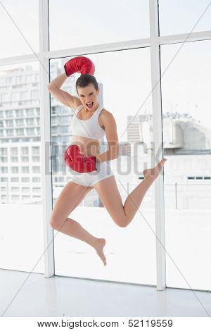 Motivated fit brown haired model in sportswear jumping in bright fitness studio