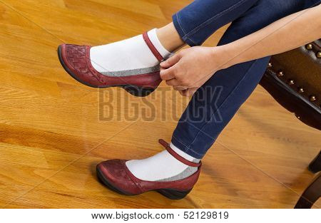 Woman Putting On Causal Shoes While Sitting On Footstool At Home
