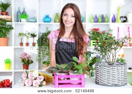 Beautiful girl florist with flowers in flowers shop 