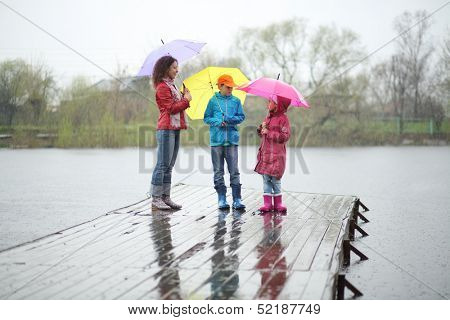 Mother and two children standing in the rain on a wooden pier