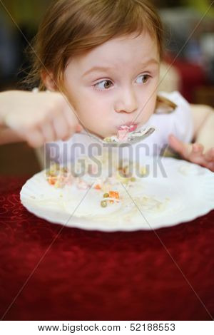 Little girl with a surprised expression on her face eating spaghetti in a cafe