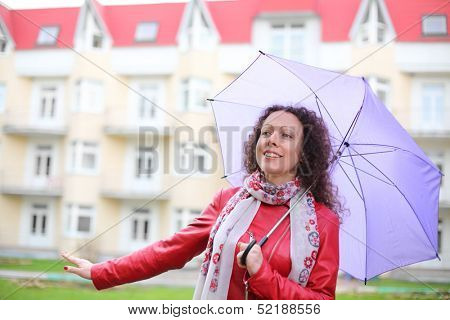 A young woman in a red jacket with a purple umbrella on the street