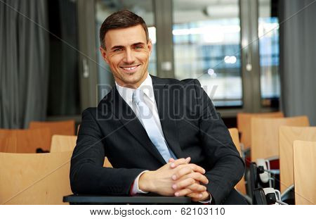 Happy businessman standing at conference hall