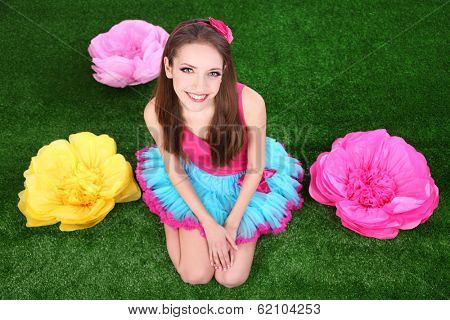Beautiful young woman in petty skirt with flowers on grass
