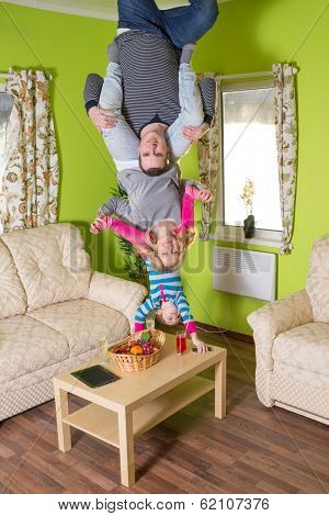 Family of three upside down on the ceiling at inverted house