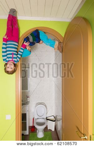 Two children upside down on the ceiling near toilet at inverted house