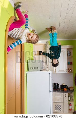 Two children upside down on the ceiling of kitchen at inverted house