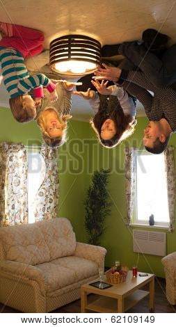 Family of four sits on the ceiling upside down with candles at inverted house
