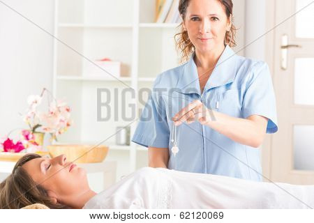 Alternative medicine therapist using pendulum to make a diagnosis