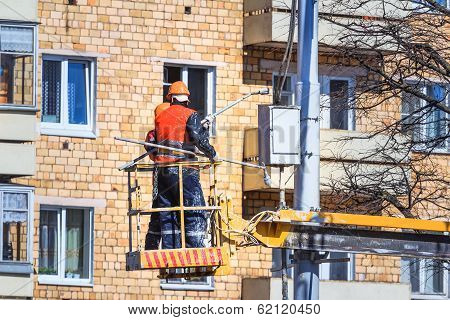 workers in aerial work platform paint light fixture