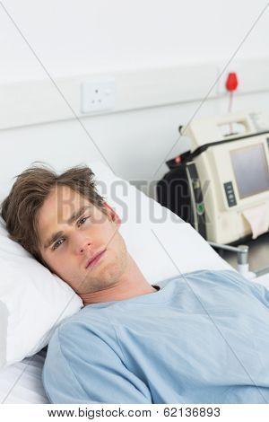Portrait of young male sick man lying in hospital bed
