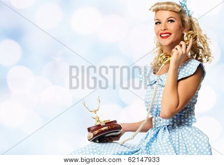 Coquette blond pin up style young woman in blue dress with vintage phone 