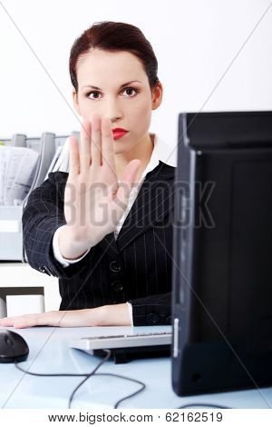 Beautiful business woman is keeping her hand ahead, making stop sign.