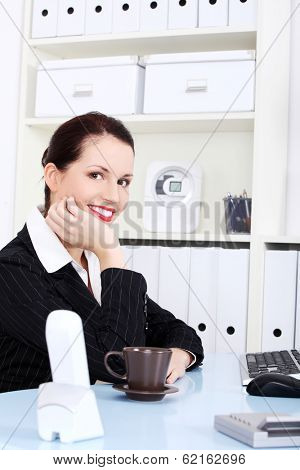 Young beautiful business woman is having break with cup of coffee or tea.