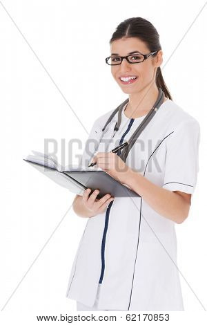 Young female doctor wirting in a book. Isolated on white. 