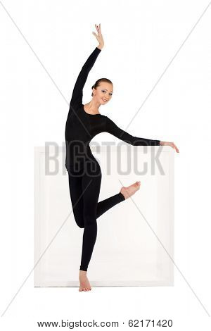 Modern bellet dancer posing with a cube at studio. Plastic body concept. Isolated over white.