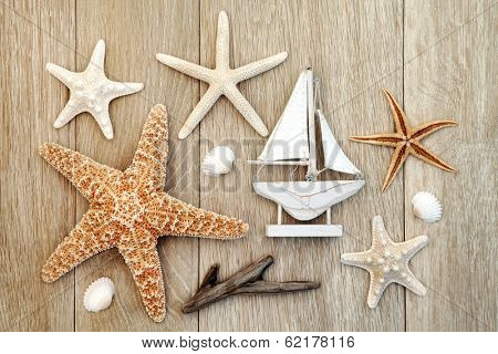Sea shell and driftwood abstract design with small boat over old oak background.